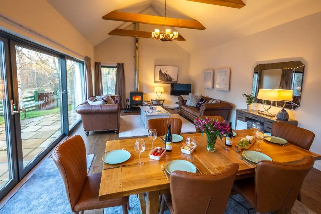 a living room with a wooden table and chairs at Riverside Lodge - Seasgair Lodges in Nethy Bridge