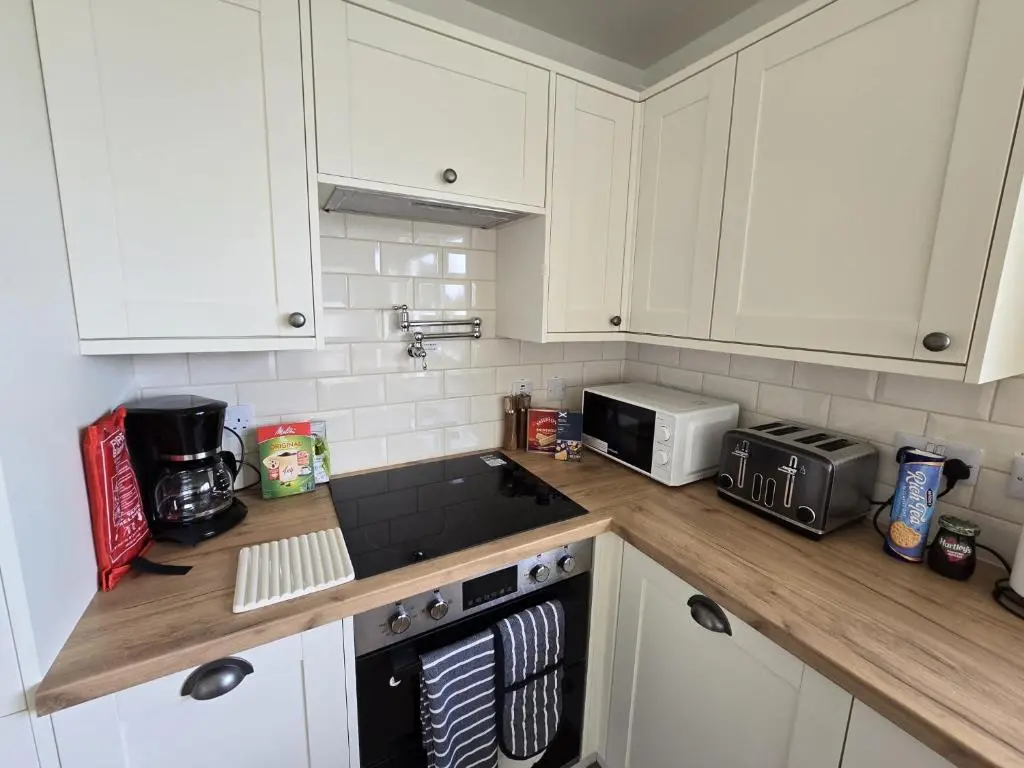 a kitchen with white cabinets and a counter top at Linden Cottage in Fortrose