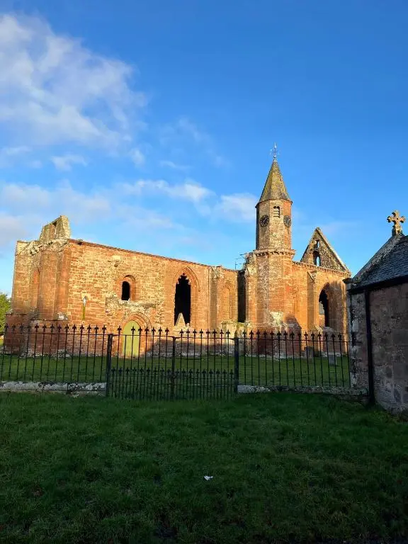 an old brick church with a fence in front of it at Linden Cottage in Fortrose
