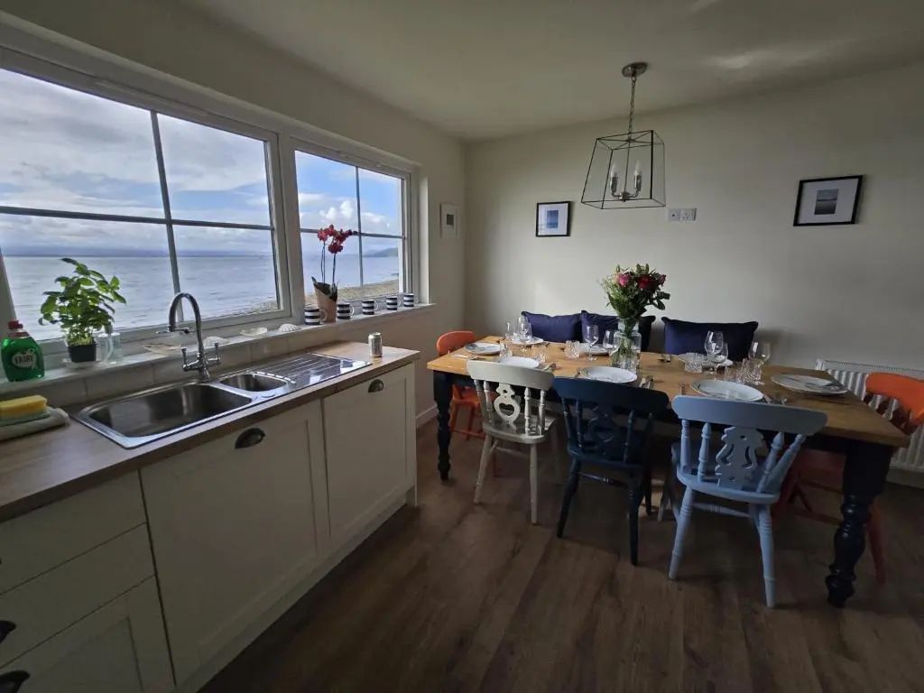 a kitchen with a table with chairs and a large window at Linden Cottage in Fortrose