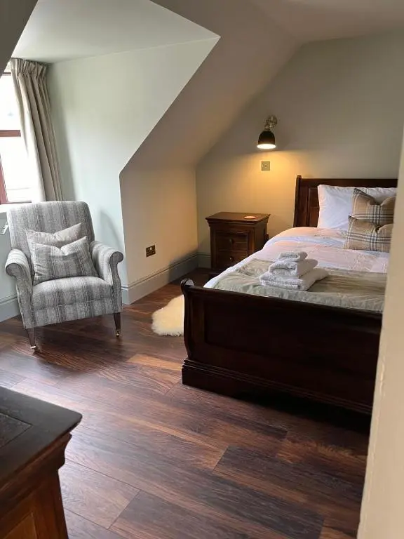 a bedroom with a bed and a chair and a window at Lewis Lodge - Stunning & Exclusive Luxury Home in the Heart of Ballater, Royal Deeside in Ballater