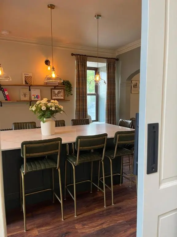 a kitchen with a large kitchen island with green chairs at Lewis Lodge - Stunning & Exclusive Luxury Home in the Heart of Ballater, Royal Deeside in Ballater
