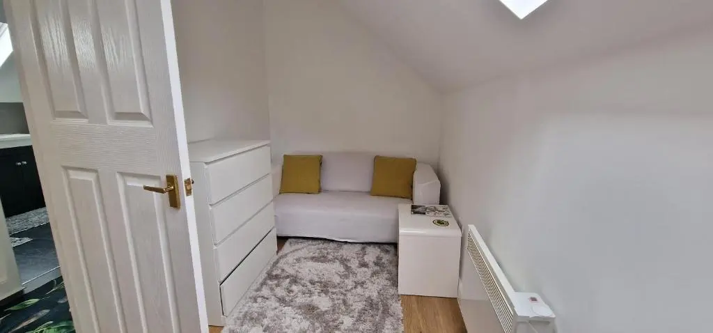 a small white room with a couch and a table at The Flat at Clocktower Buildings in Kinloss