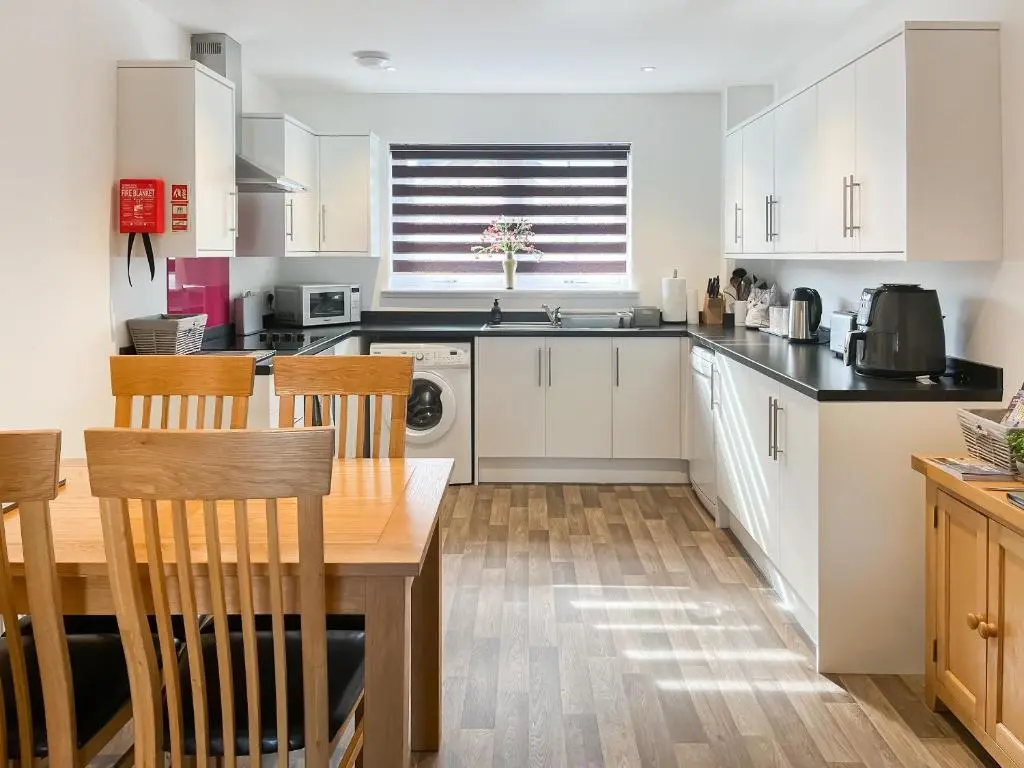 a kitchen with white cabinets and a table and chairs at No 8 Cottage in Aviemore