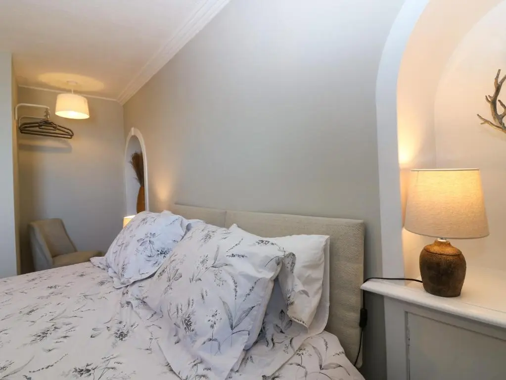 a bedroom with a bed with white sheets and a lamp at West Pier Cottage in Macduff