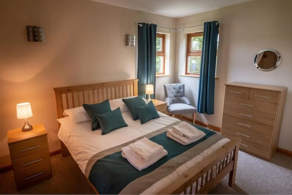 a bedroom with a large bed with blue curtains at Findhorn Bay - Sandpiper Eco chalet in Findhorn