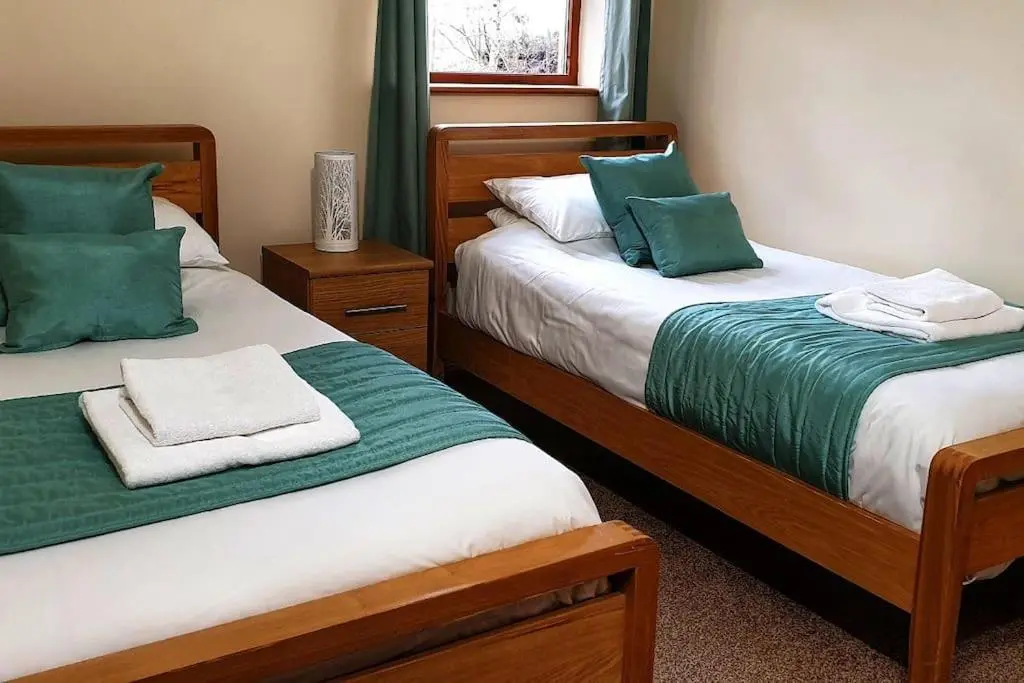 two beds with green and white pillows in a room at Findhorn Bay - Sandpiper Eco chalet in Findhorn