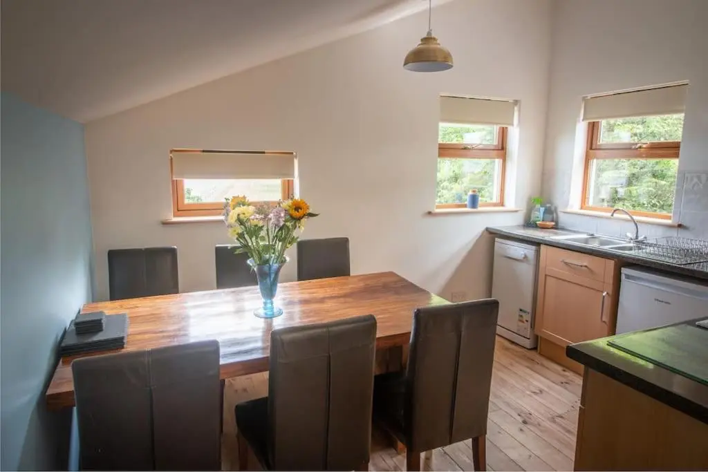 a kitchen with a wooden table with a vase of flowers on it at Findhorn Bay - Sandpiper Eco chalet in Findhorn