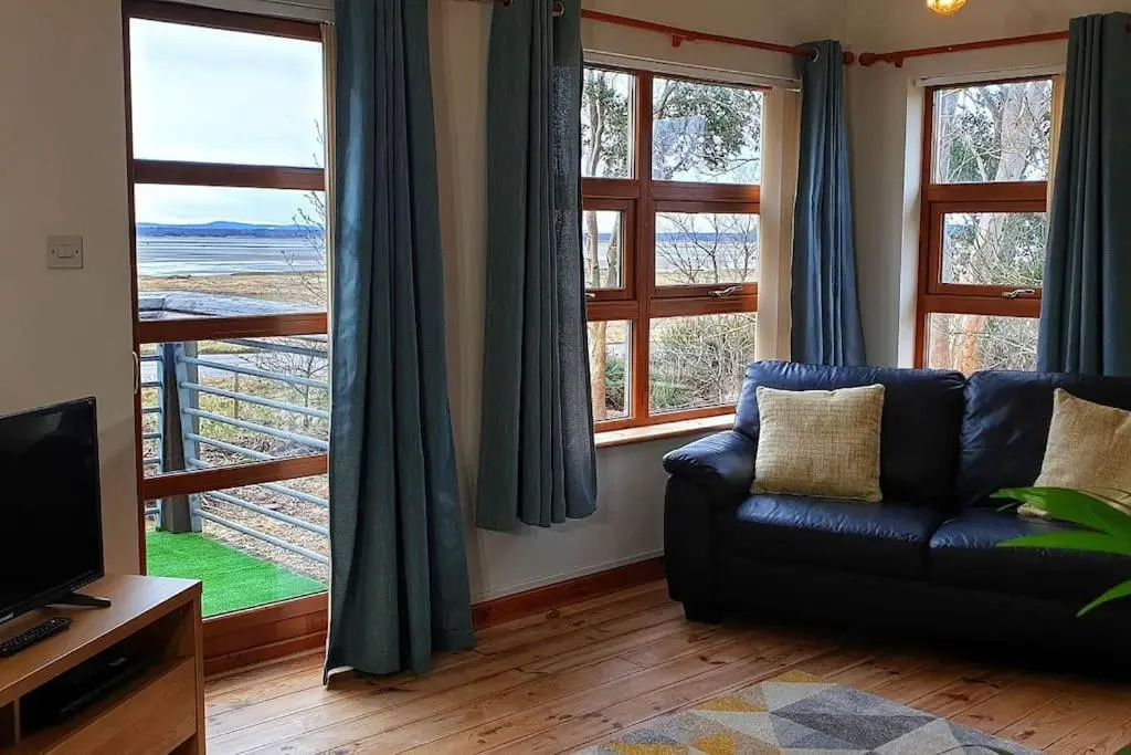 a living room with a couch and large windows at Findhorn Bay - Sandpiper Eco chalet in Findhorn