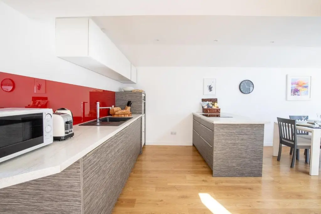 a kitchen with red and white cabinets and a microwave at Cairnie Cottage in Ballater