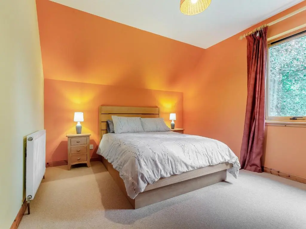 a bedroom with orange walls and a bed and a window at Bridge House in Evanton