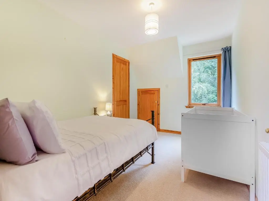 a bedroom with a white bed and a window at Bridge House in Evanton