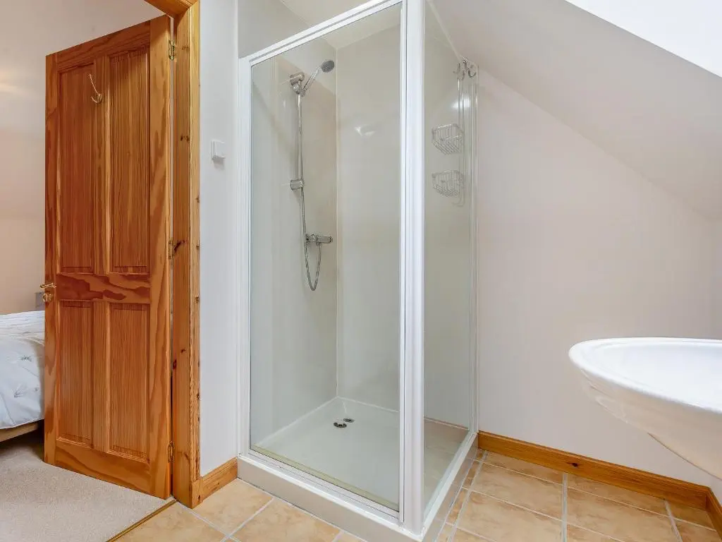 a bathroom with a glass shower and a sink at Bridge House in Evanton