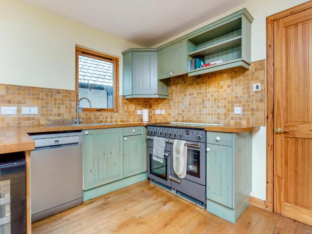 a kitchen with blue cabinets and a sink at Bridge House in Evanton