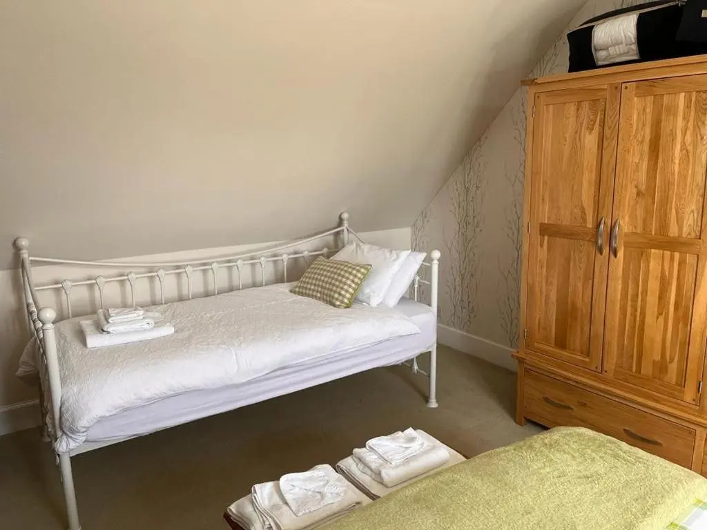 a bedroom with a white bed and a wooden cabinet at The Nairn House in Nairn