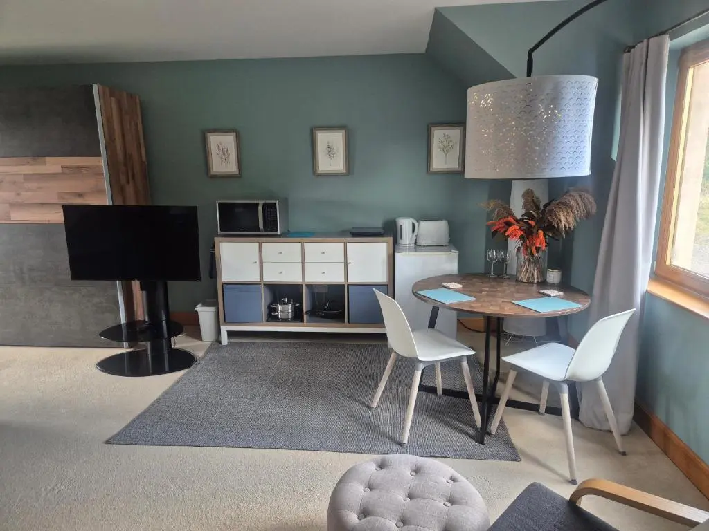 a living room with a table and chairs and a television at Twin Pines in Mulben