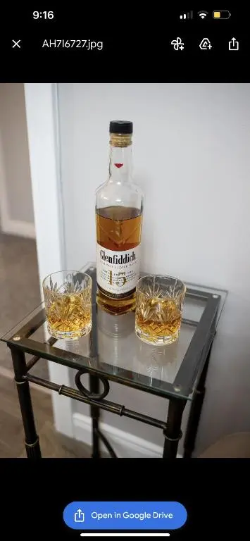 a bottle of whiskey and two glasses on a glass table at Inverness Apartment - Uist in Inverness