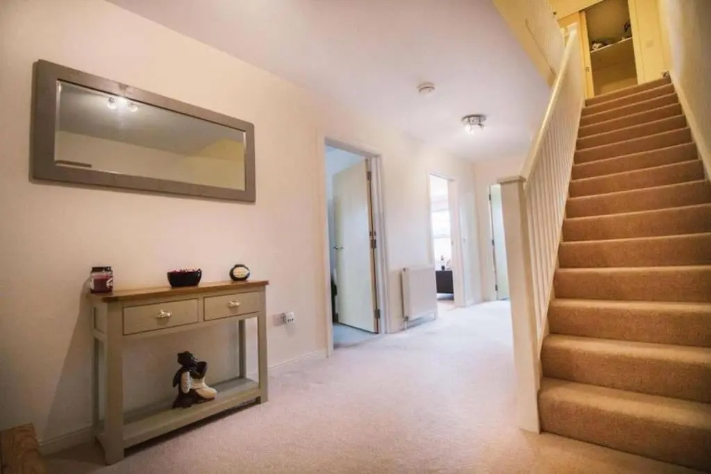 a hallway with a staircase and a mirror on the wall at Inverurie Town Centre 97m2 Maisonette in Inverurie