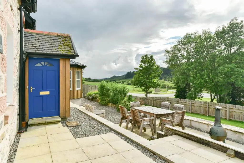 a patio with a blue door and a table and chairs at Cosy Spacious Highland Cottage in Craggie