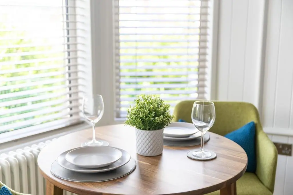 a wooden table with two wine glasses and a potted plant at Hillside Luxury Apartments in Inverness