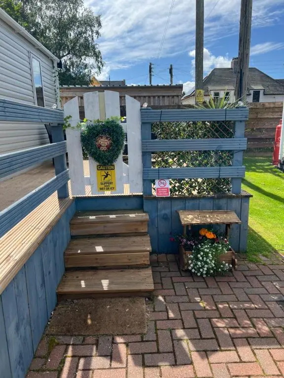 a blue fence with a wooden staircase and flowers at 44 Angels Retreat in Boat of Garten