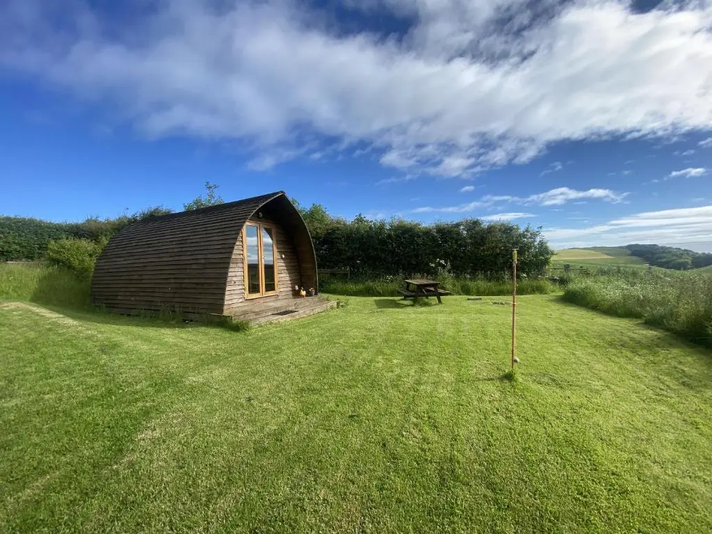 a small wooden cabin in a field of grass at Greenley Croft Glamping by Wigwam in Crovie