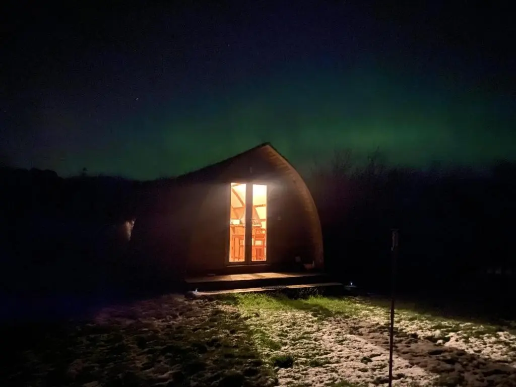 an igloo with a window at night with the northern lights at Greenley Croft Glamping by Wigwam in Crovie