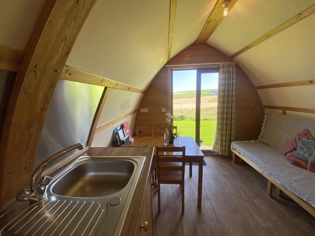 a kitchen with a sink and a table in a room at Greenley Croft Glamping by Wigwam in Crovie