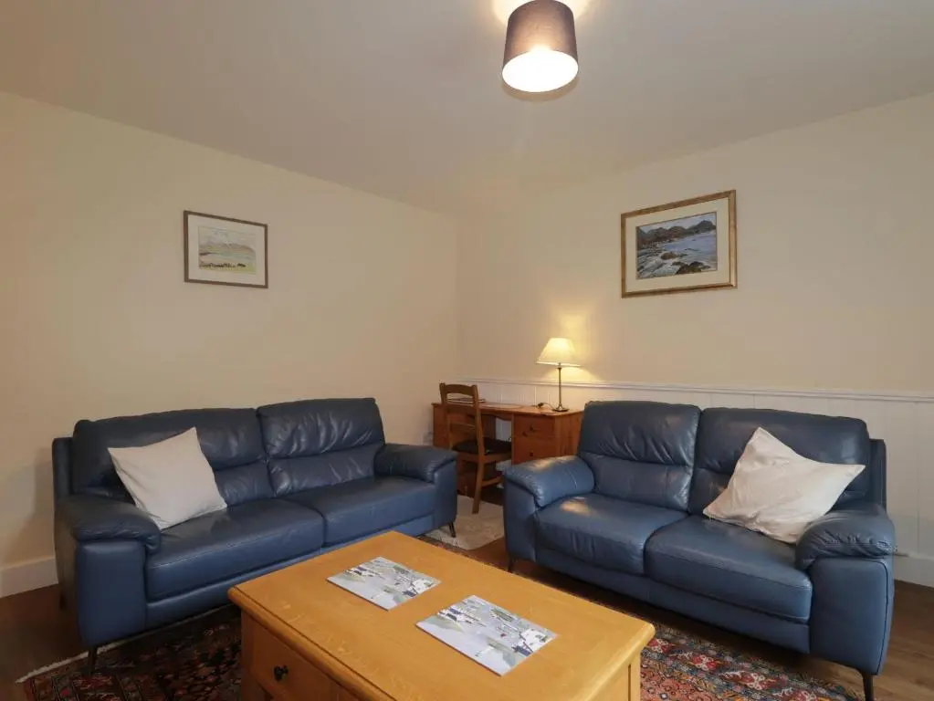 a living room with two blue couches and a table at Gunroom Cottage in Strathpeffer