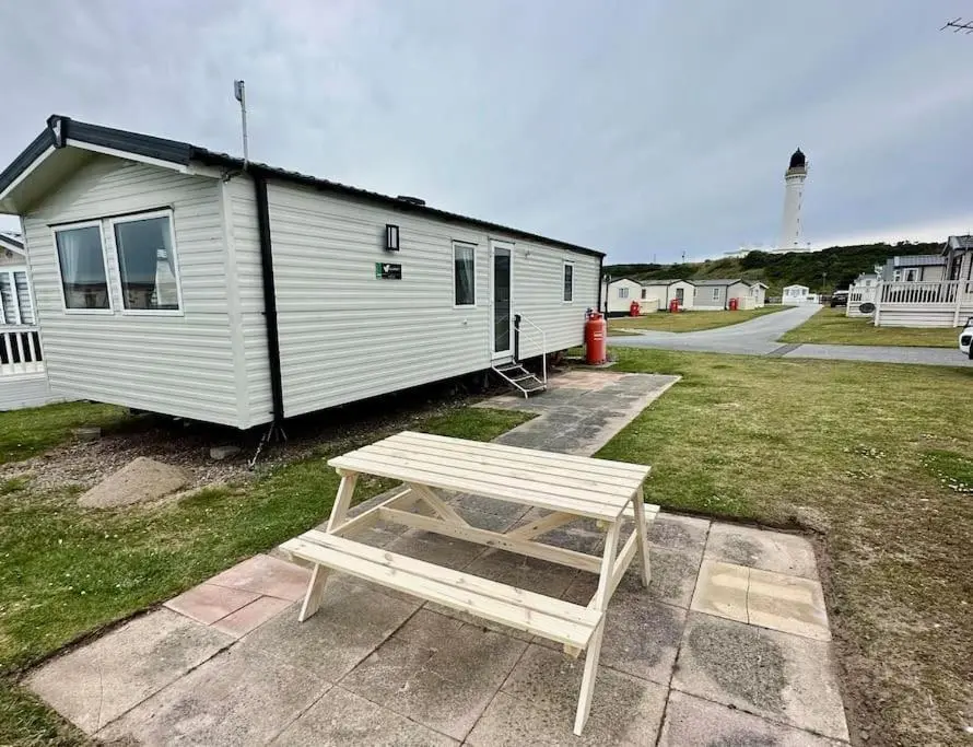 a wooden bench sitting in front of a building at Sea La Vie Caravan at Silver Sands Holiday Park in Lossiemouth