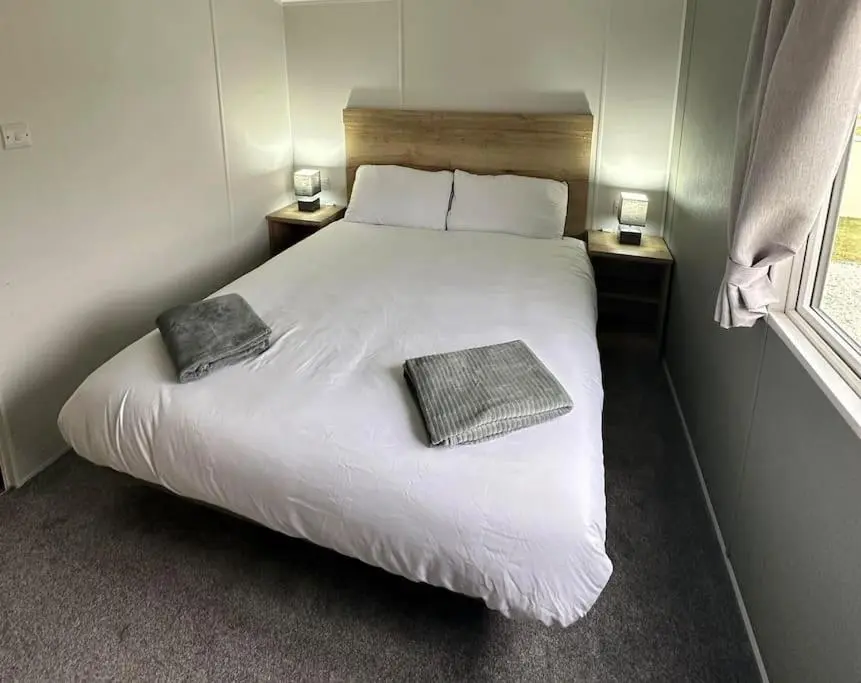 a bedroom with a white bed with two pillows on it at Sea La Vie Caravan at Silver Sands Holiday Park in Lossiemouth