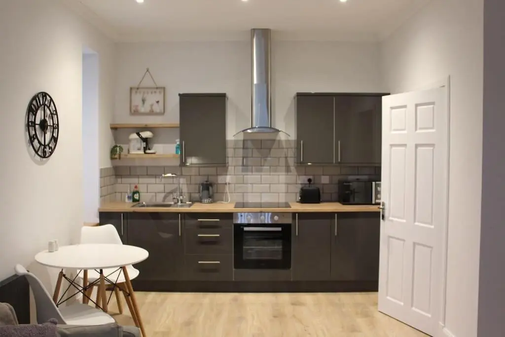 a kitchen with brown cabinets and a table and a door at One bedroom Flat in Dingwall in Dingwall