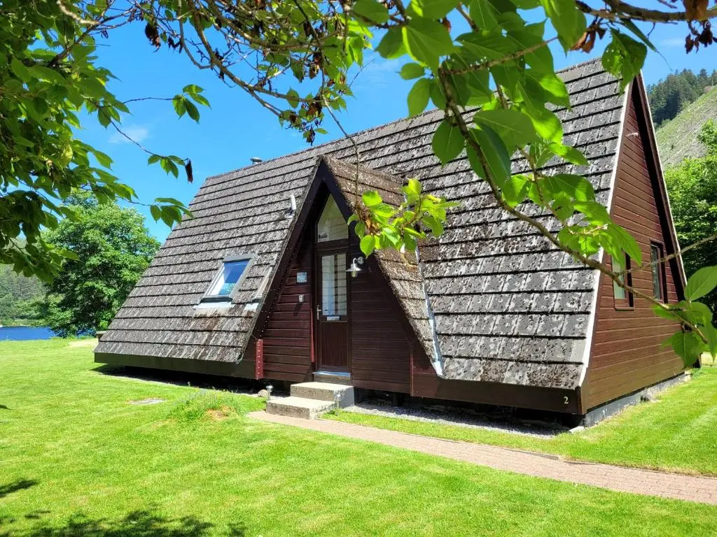 a house with a gambrel roof on a grass field at Lodge 2 - Inglewood Lodge in Spean Bridge