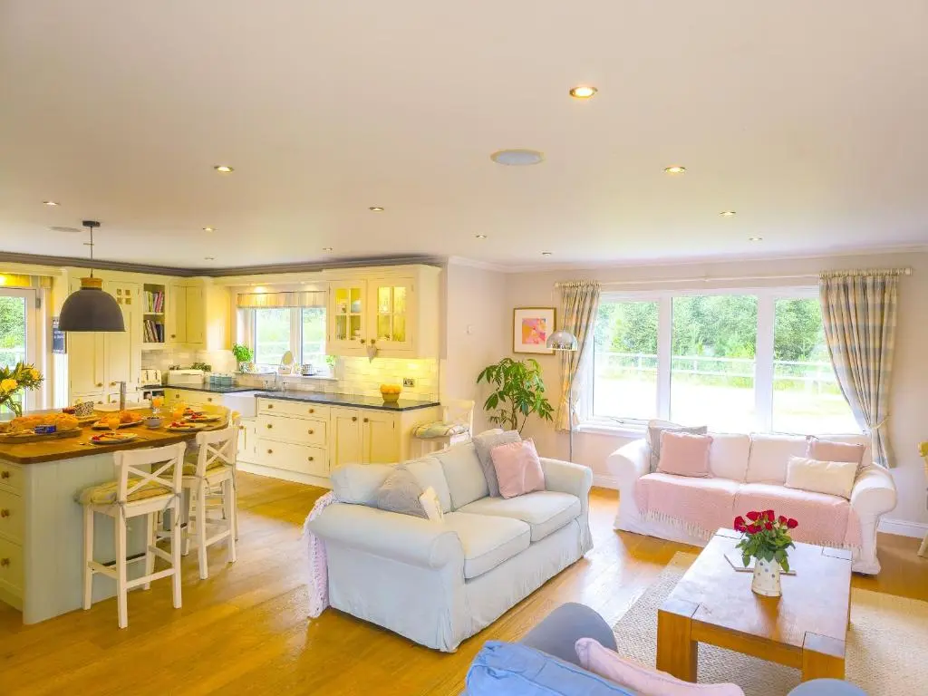 a living room with two couches and a kitchen at The Bellhouse - hot tub lodge in Tomatin in Tomatin