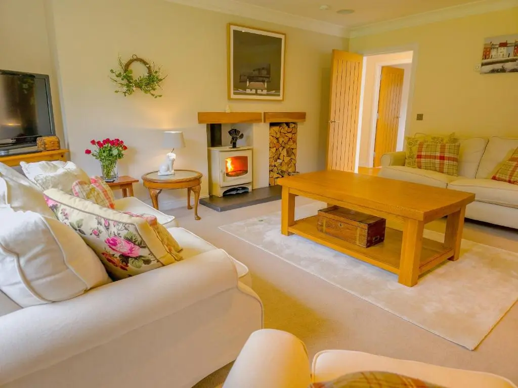 a living room with a couch and a table at The Bellhouse - hot tub lodge in Tomatin in Tomatin