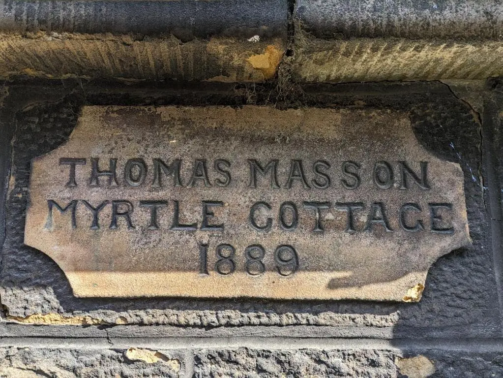 a stone sign on the side of a building at Myrtle Cottage Findhorn in Forres