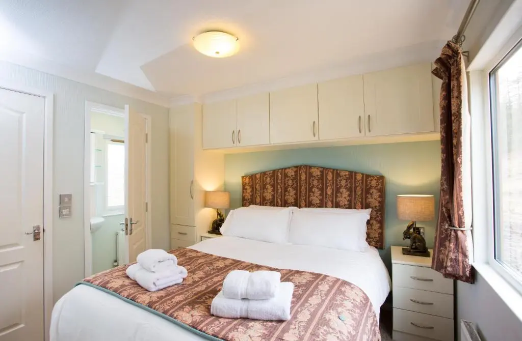 a bedroom with a bed with towels on it at Bluebell Lodge - Sleeps 4 Loch & Woodland in Strathpeffer