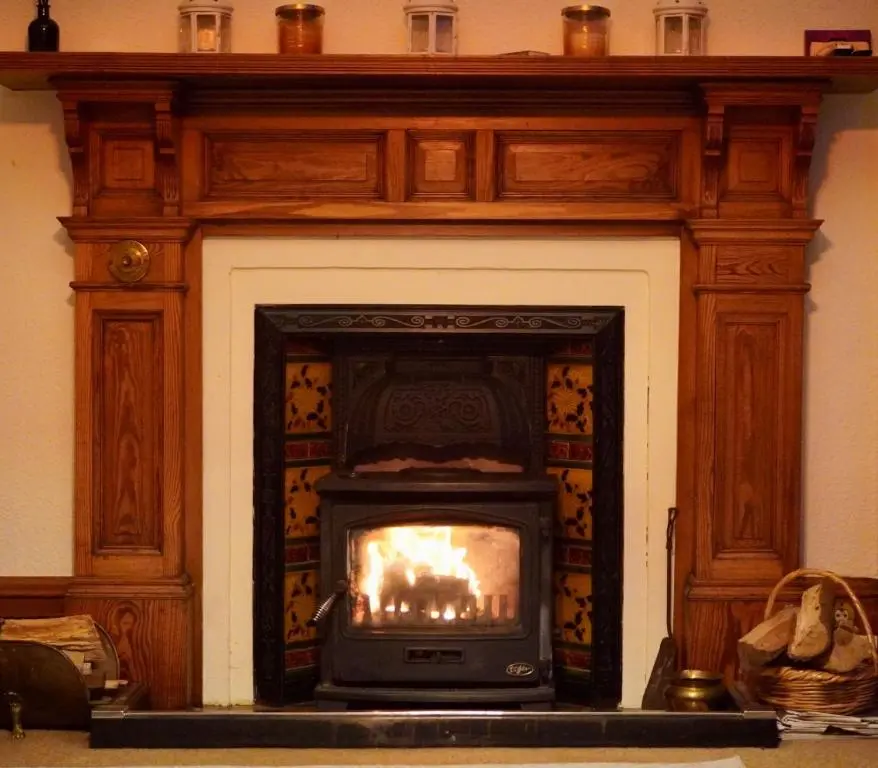 a fireplace with a fire in it in a room at Ardchoile in Kingussie