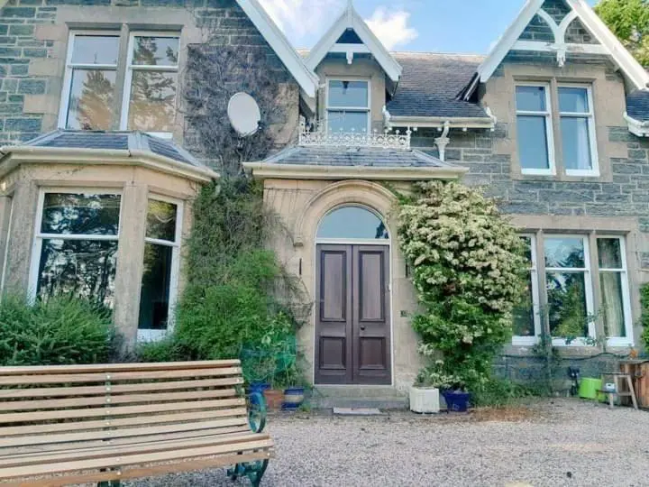 a house with a wooden bench in front of it at Ardchoile in Kingussie