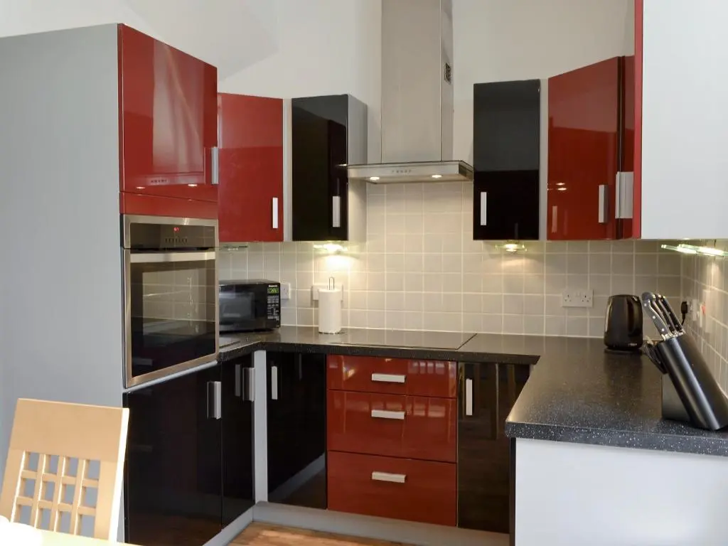 a kitchen with red cabinets and black counter tops at Viewington Lodge in Ballater