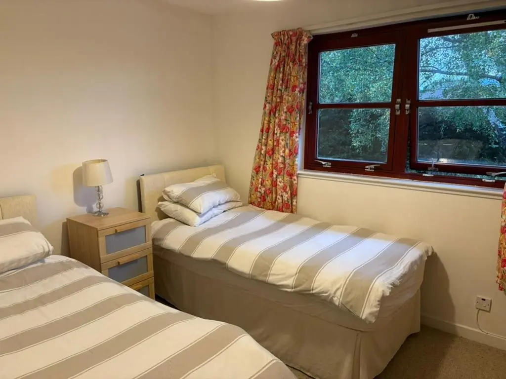 two beds in a room with a window at Craigie View Aviemore in Aviemore
