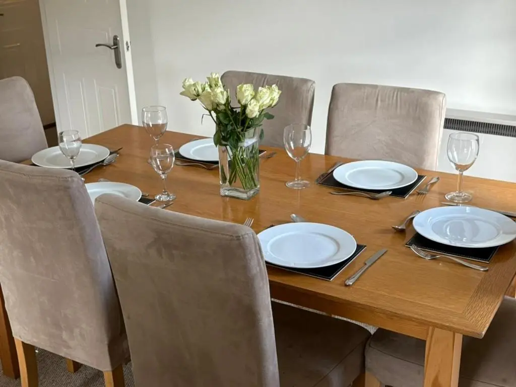 a wooden table with chairs and plates and a vase of flowers at Craigie View Aviemore in Aviemore