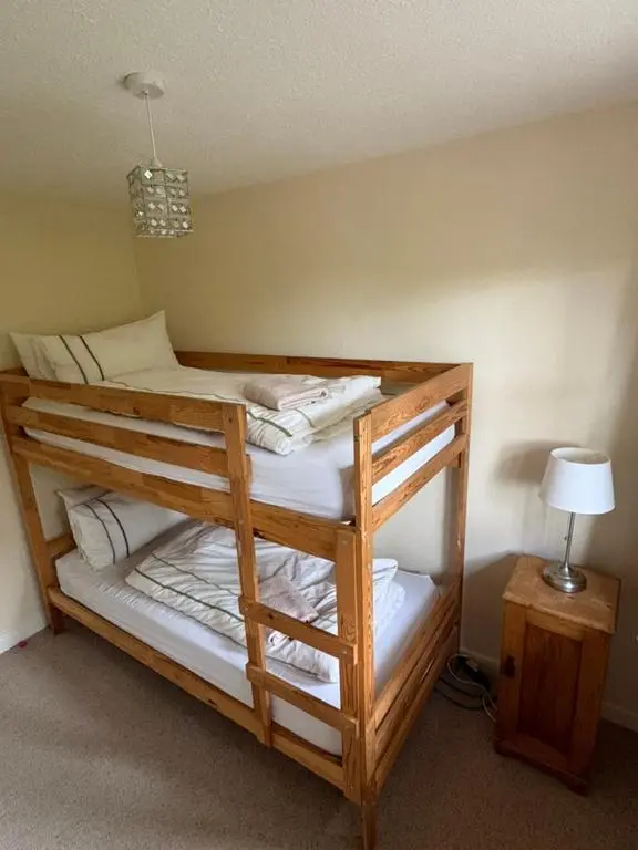 a wooden bunk bed in a room with a lamp at Craigie View Aviemore in Aviemore