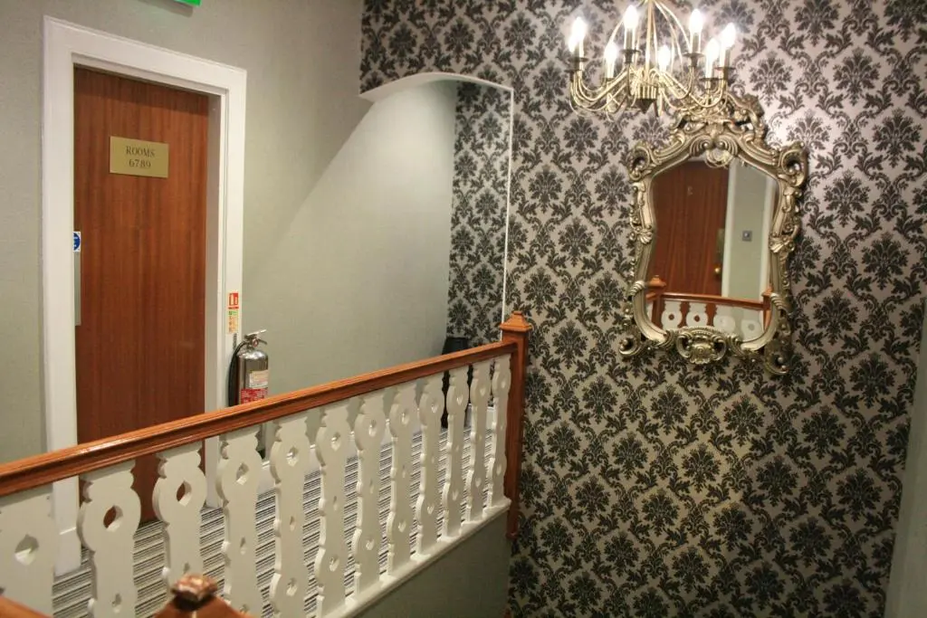 a hallway with a staircase with a mirror and a chandelier at North Kessock Hotel in Inverness