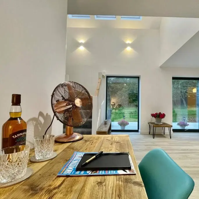 a room with a wooden table with a fan on it at The Clearing in Huntly