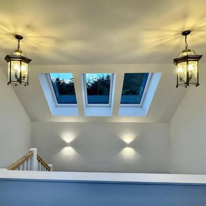 a room with three windows and lights on the wall at The Clearing in Huntly