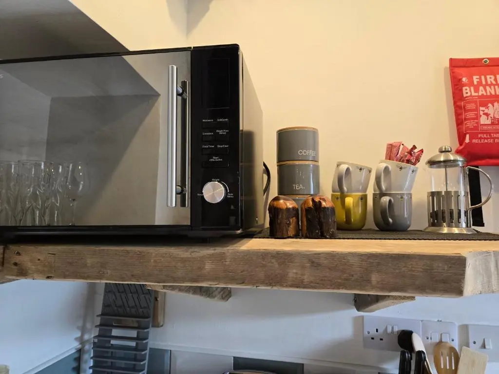 a microwave on a wooden shelf in a kitchen at The Wee Bothy in Tain
