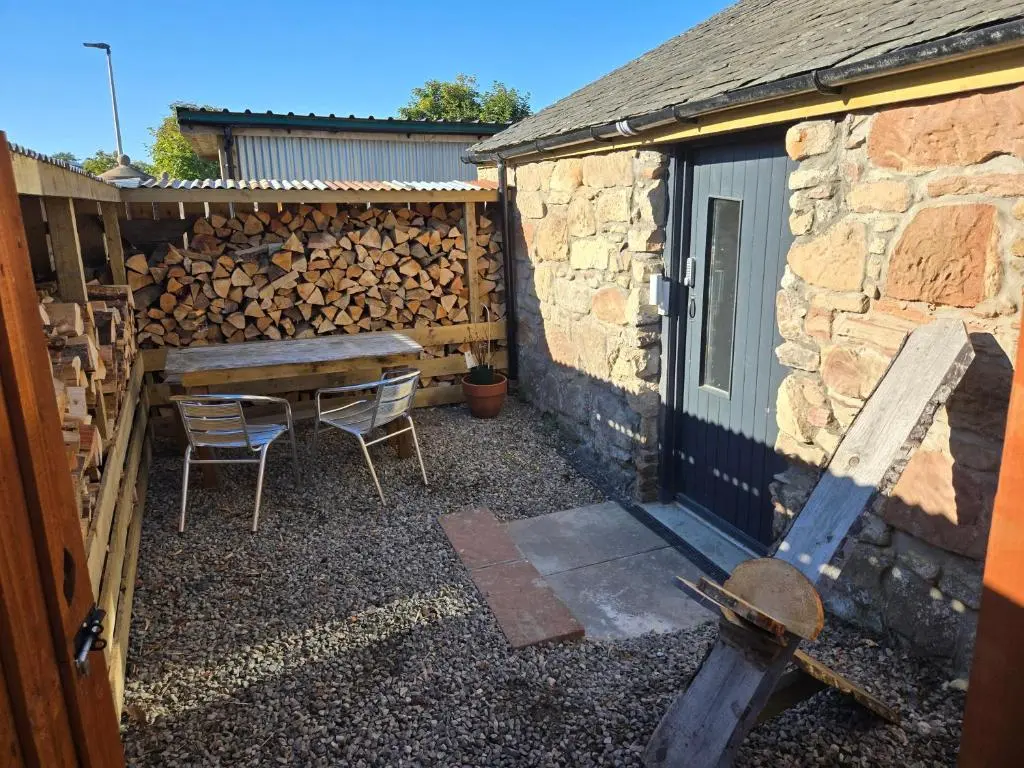 a patio with a table and chairs next to a fence at The Wee Bothy in Tain