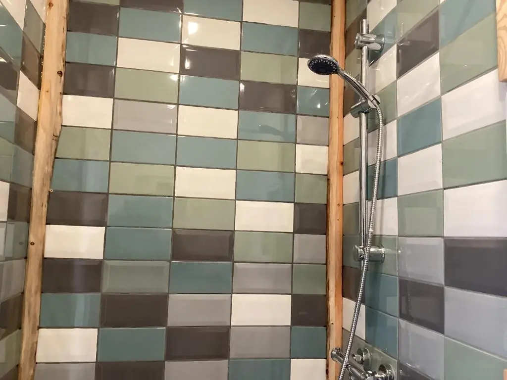 a bathroom with a shower with tiled walls at The Wee Bothy in Tain
