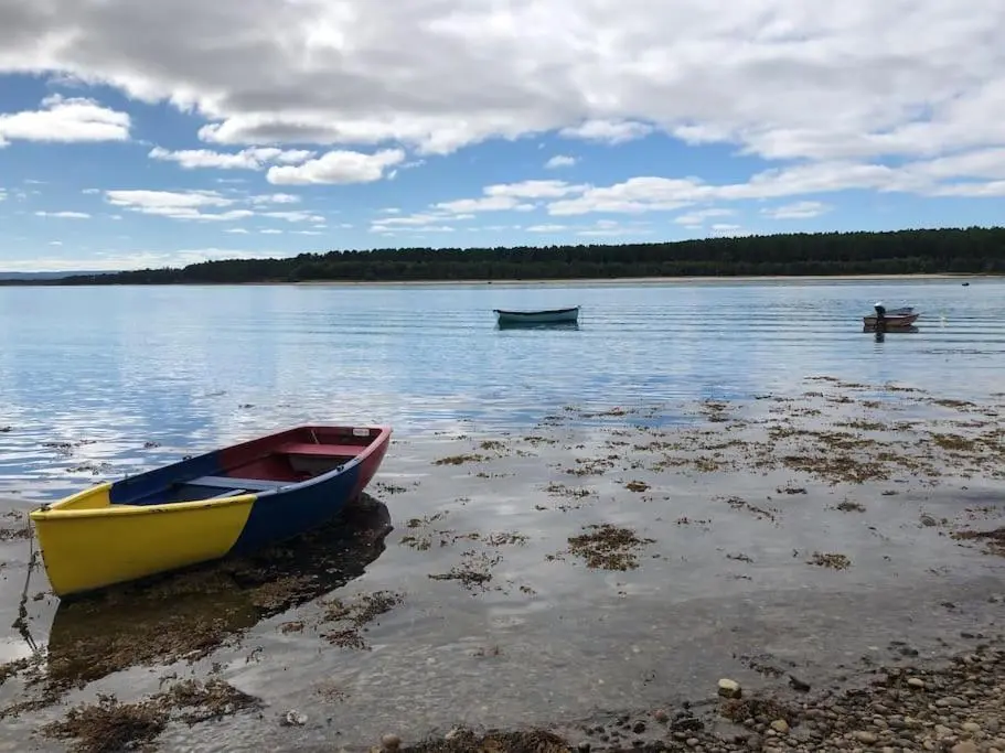 two boats sitting on the shore of a lake at Calailan Highland Seaside Retreat - Nairn in Nairn